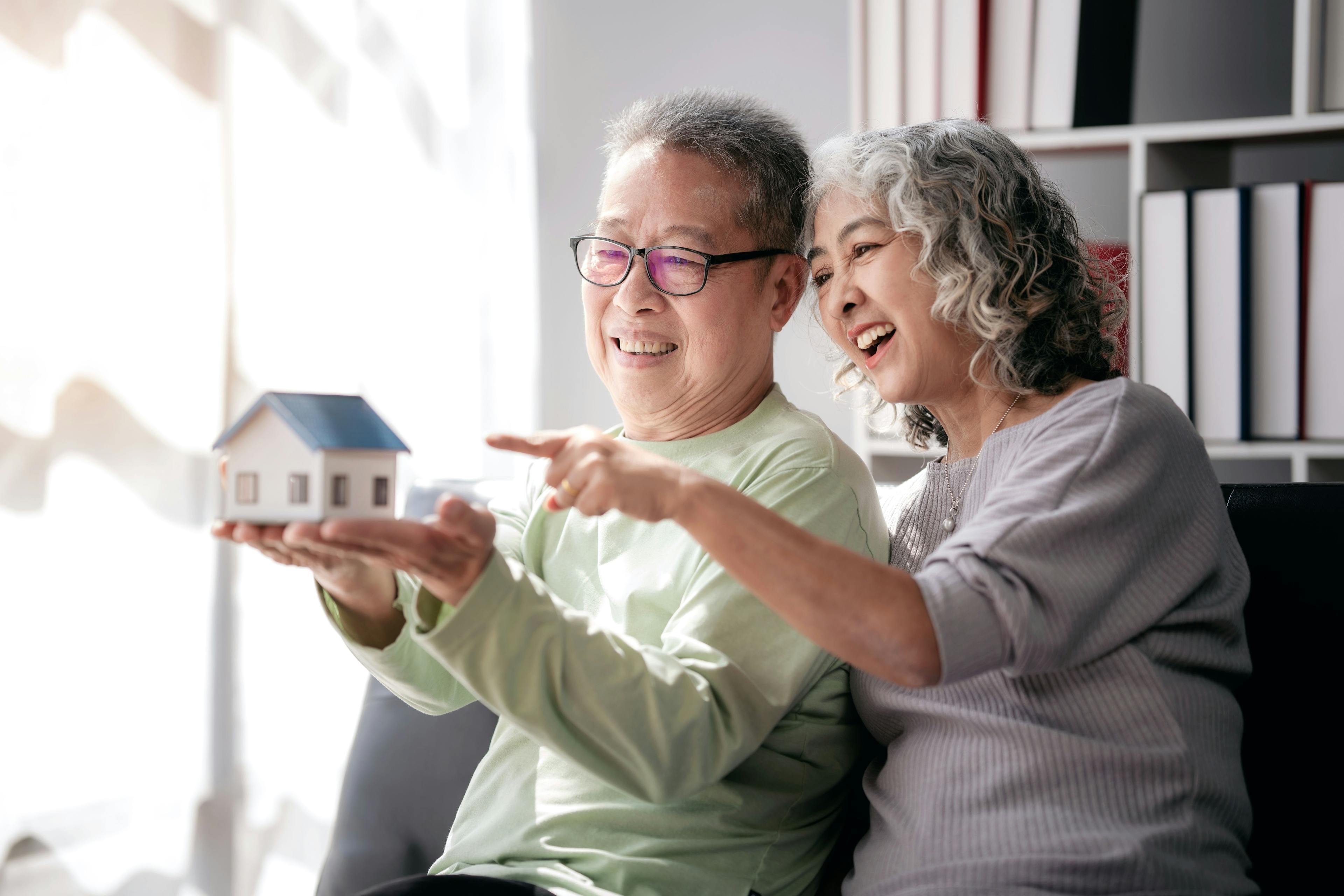 Thema Pensionierung und Hypothek: Ein älteres Paar mit einem Hausmodell. 